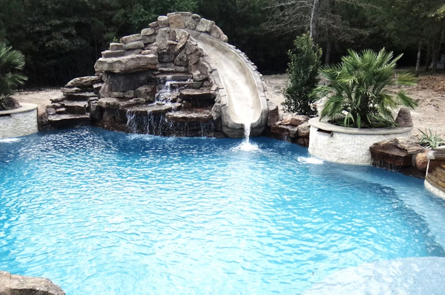 A pool with a waterfall and slide.